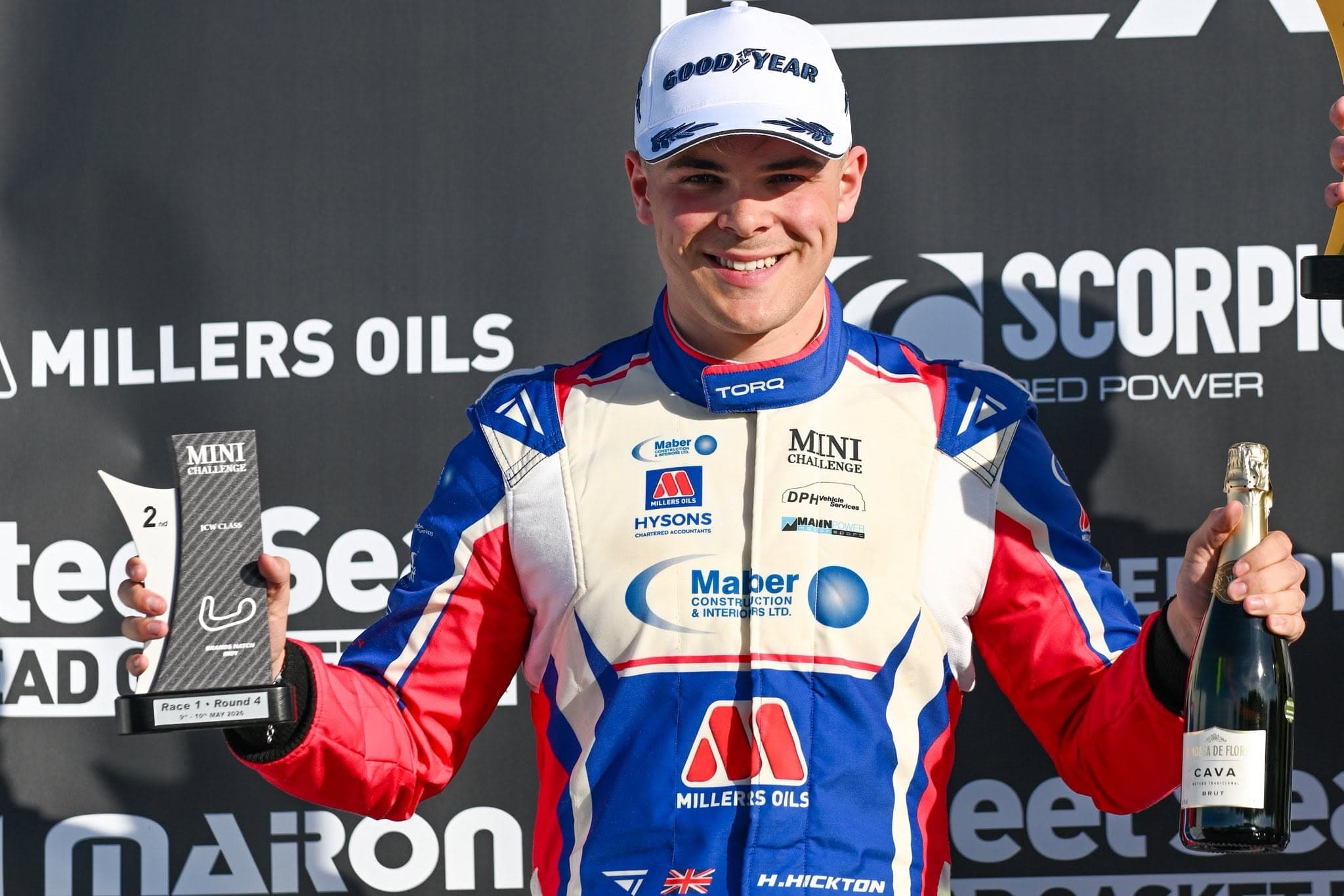 Harry Hickton on the podium holding his trophy wearing a blue, white and pink Torq Racecraft
