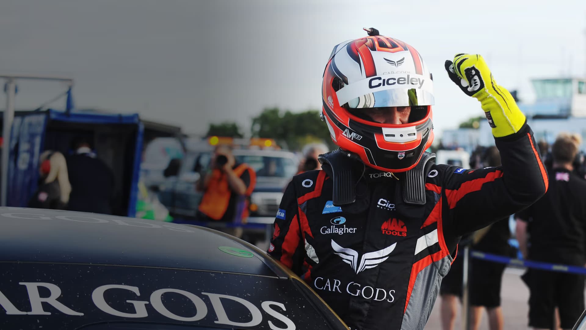 Driver wearing a bespoke Torq race suit beside a race car.