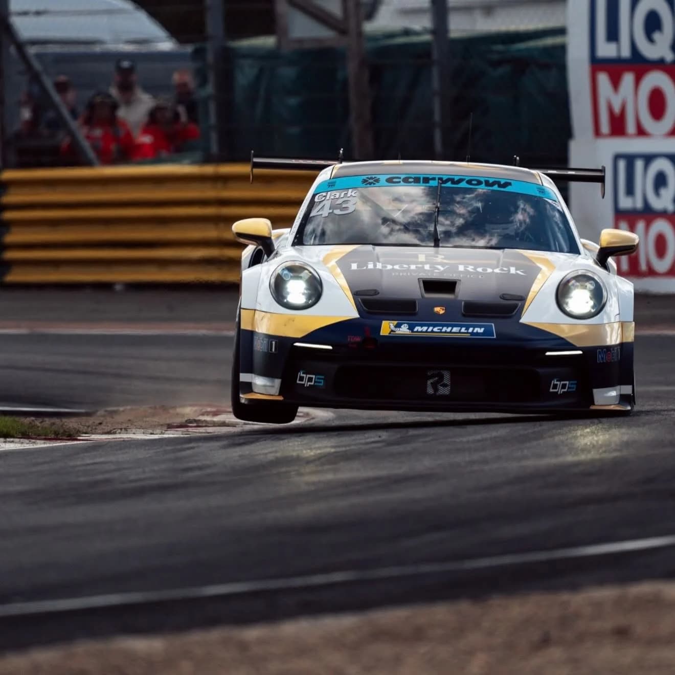 Archie Clark’s number 43 Porsche on track in gold, black and white livery.