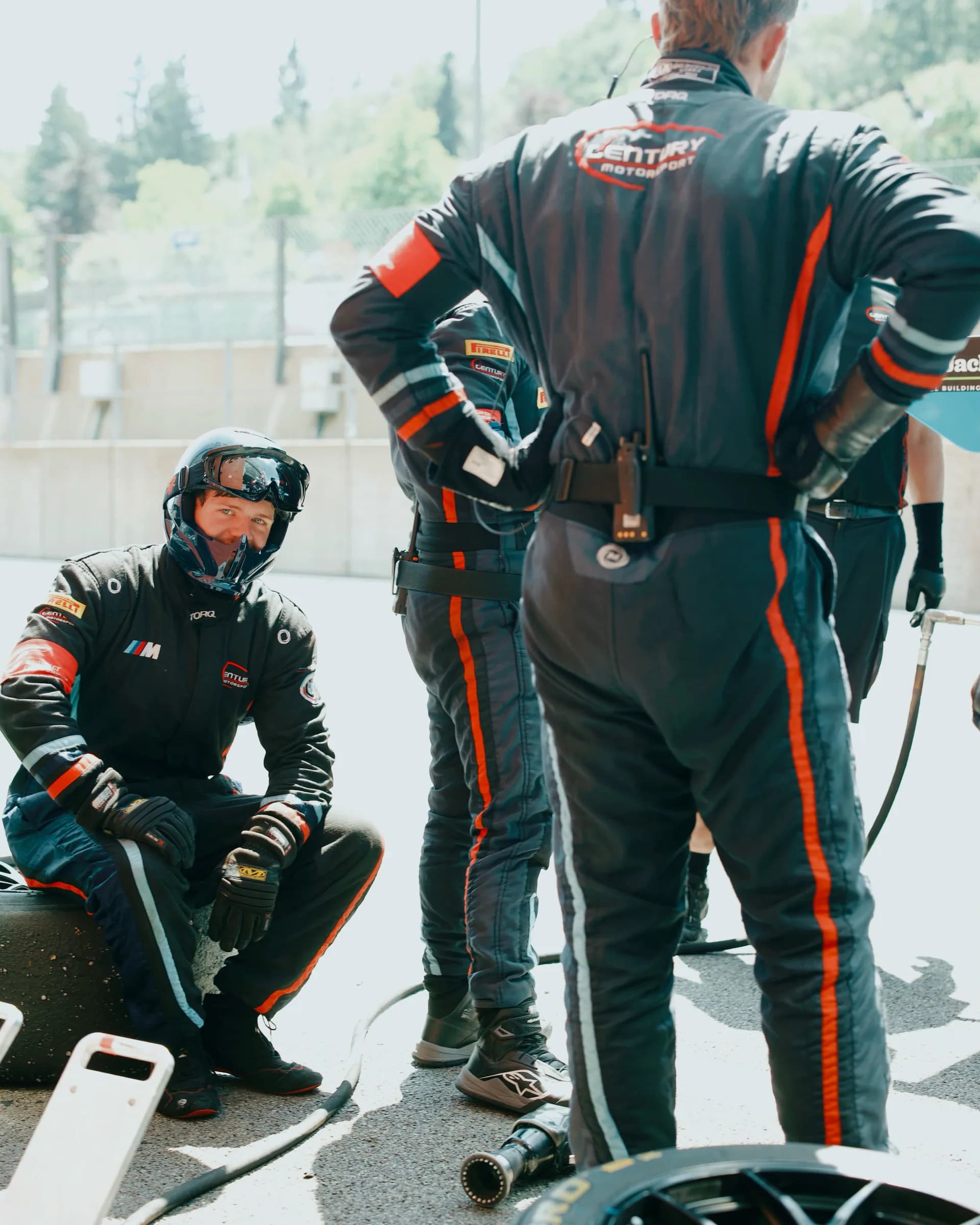 Torq mechanics in coordinated black team suits preparing beside a race car in the pit lane.
