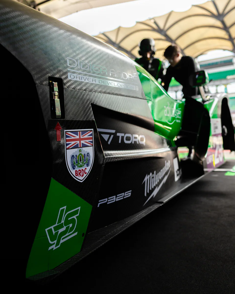 Close-up of a Torq-branded green and black prototype race car inside a garage.